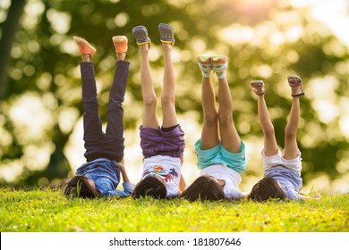 春の公園で屋外の緑の草の上に横たわる幸せな子供たちのグループ