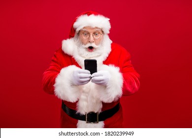 Retrato de su agradable atractivo guapo sorprendido asombrado Santa usando gadget 5g blogger de blog de velocidad rápida navegación multimedia aislado sobre fondo de color rojo vibrante brillante brillante