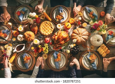 Sekelompok teman atau anggota keluarga mengucap syukur kepada Tuhan di meja makan malam kalkun yang meriah bersama. Konsep makan malam tradisional perayaan Thanksgiving