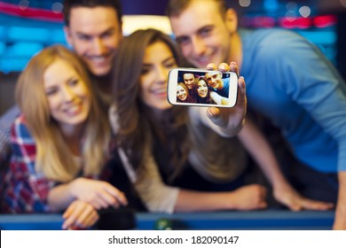 Lachende vrienden nemen selfie foto van nachtclub met biljart