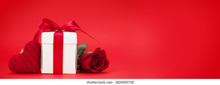 Valentijnsdag brede wenskaart met roze bloem en geschenkdoos voor rode achtergrond met ruimte voor uw groeten