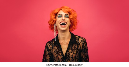 赤い背景で笑っているドラッグ クイーンの肖像画。笑っている女性に扮した性別流動的な男性。