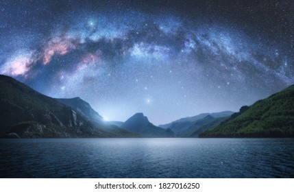 Vía Láctea arqueada sobre las hermosas montañas y el mar azul por la noche en verano. Paisaje colorido con cielo estrellado brillante con arco de la Vía Láctea, luz de la luna, constelación, agua. Galaxia. Naturaleza y espacio