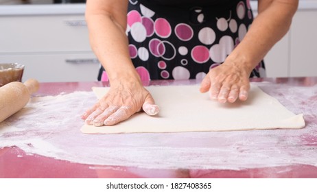 Cooking dough with a rolling pin on the table. Working at the bakery. Grandmother cook in the kitchen prepares dough from flour, concept of food, diet and bio. High quality 4k footage