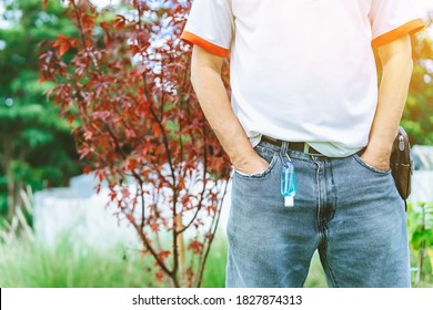 Mini portable alcohol gel bottle to kill Corona Virus(Covid-19) hanging on belt loop of man' s jeans with plants background. New normal lifestyle. Health care concept. Selective focus on alcohol gel