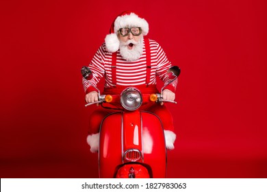 Retrato de su guapo padre de Santa barbudo asombrado impresionado montando ciclomotor entregando regalos tradición viaje velocidad rápida apresuramiento aislado brillante vivo brillo vibrante fondo de color rojo