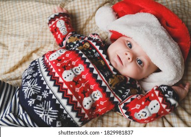 Lễ giáng sinh. Cậu bé sơ sinh đáng yêu đội mũ ông già Noel và áo len Giáng sinh đang nằm trên giường. Nhìn từ trên cao.