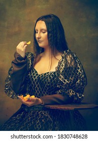 Lekkerste frietjes. Jonge vrouw als Mona Lisa, La Gioconda geïsoleerd op donkergroene achtergrond. Retro stijl, vergelijking van tijdperken concept. Mooi vrouwelijk model zoals klassiek historisch karakter, oud