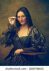 Bril roze. Jonge vrouw als Mona Lisa, La Gioconda geïsoleerd op donkergroene achtergrond. Retro stijl, vergelijking van tijdperken concept. Prachtig vrouwelijk model als klassiek historisch karakter, ouderwets.