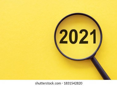 Tập trung vào khái niệm kinh doanh. Kính lúp với số từ 2021 trên bảng màu vàng. Khái niệm kinh doanh trong năm mới. Tìm kiếm ý tưởng