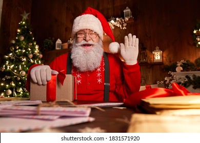 Feliz Papá Noel, San Nicolás sosteniendo una carta mirando a la cámara, hablando con videollamadas por cámara web o grabando Feliz año nuevo, saludos de Feliz Navidad en la víspera de Navidad sentado a la mesa tarde en casa.