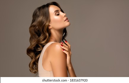 Beautiful woman in profile  with long  and   shiny wavy  hair .  Beauty  model girl with curly hairstyle .