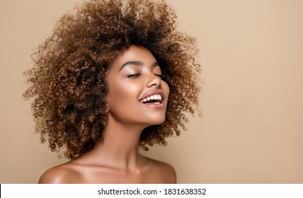 Retrato de belleza de niña afroamericana con piel limpia y saludable sobre fondo beige. Sonriente soñadora hermosa mujer negra.Pelo rizado en estilo afro