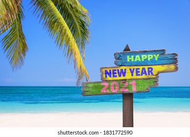 色付きの木製の方向標識、ビーチ、ヤシの木の背景に新年あけましておめでとうございます2021