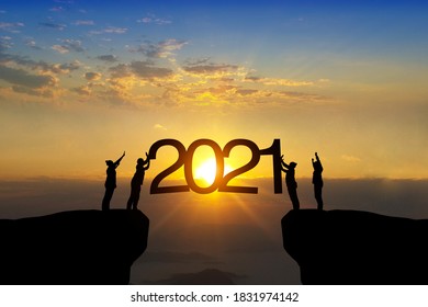 Silhouet van gelukkig teamwerk dat staat en 2021-tekst aanraakt op prachtige zonsopgangachtergrond, vier zakelijk succes en groei tot het jaar 2021.