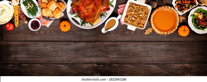 Traditioneel Thanksgiving-kalkoendiner. Boven de bovenrand van het aanzicht op een donkere houten bannerachtergrond met kopieerruimte. Kalkoen, aardappelpuree, dressing, pompoentaart en bijgerechten.