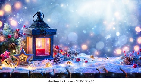 Weihnachtslaterne mit Tannenzweig und Dekoration auf schneebedecktem Tisch - defokussierter Hintergrund