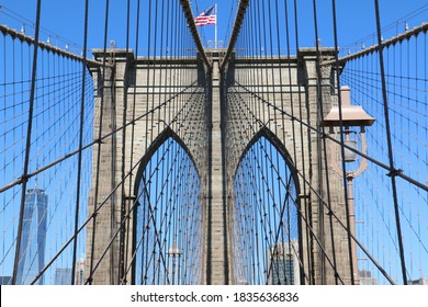 Puente de Brooklyn en la ciudad de Nueva York cerca, One World Trade Center visible. Bandera americana de los E.E.U.U. y cielo azul