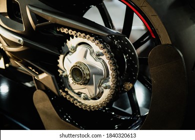 Detalle de una cadena trasera de motocicleta con tubos de escape. Vista trasera de una motocicleta con el foco en la cadena.