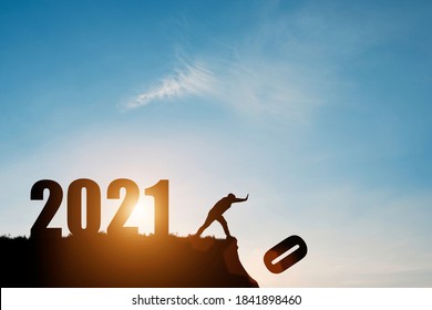 Man duwt nummer nul van de klif waar het nummer 2021 is met blauwe lucht en zonsopgang. Het staat symbool voor het starten en verwelkomen van een gelukkig nieuwjaar 2021.