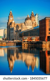 De Drie Gratiën, gezien vanaf Royal Albert Dock met historische gebouwen en weerspiegeling in Engeland, Verenigd Koninkrijk.