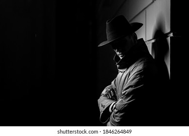 donker silhouet van een man in een regenjas met een hoed 's nachts op straat in een misdaad Noir-stijl