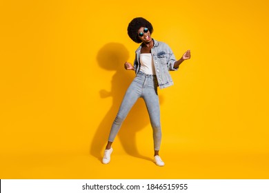 Volledige foto van een glanzende, mooie jonge dame draagt ​​een casual denim-outfit die lacht en een geïsoleerde gele achtergrondkleur dansen