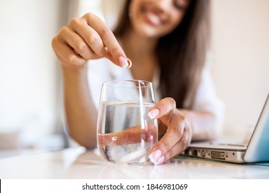 Cận cảnh một phụ nữ trẻ nhỏ thuốc kháng axit sủi bọt vào một cốc nước. Một phụ nữ trẻ khó có thể nhỏ một viên thuốc hòa tan có thuốc giảm đau hoặc thuốc giải rượu vào một cốc nước
