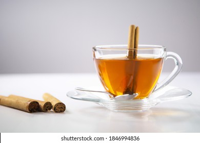 Secangkir teh, teh kayu manis, minuman kayu manis dengan batang kayu manis di kantong teh, daun dengan latar belakang putih, sendok, cangkir transparan, teh ceylon, sri lanka, kayu manis ceylon