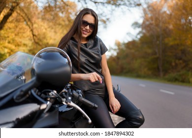 Kvindelig motorcyklist i briller og sort lædertøj sidder på en sportscykel