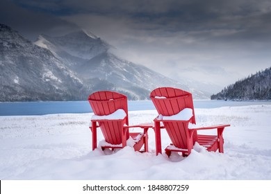 Un par de sillas de madera con vistas al Parque Nacional Waterton Lakes de Canadá durante el invierno con un lago glaciar