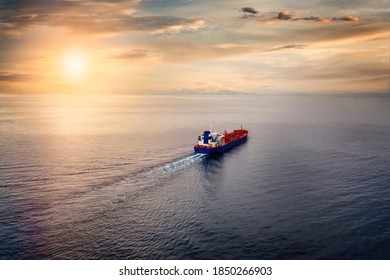 Luchtfoto van een containervrachtschip dat over een kalme zee de zonsondergang tegemoet vaart