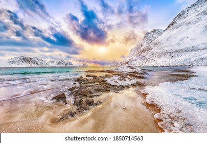 Fantastische Winteransicht des Strandes von Haukland während des Sonnenuntergangs mit viel Schnee und schneebedeckten Berggipfeln nahe Leknes. Ort: Leknes, Vestvagoy, Lofotens, Norwegen