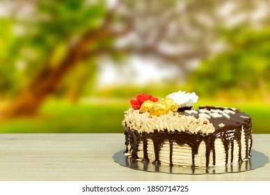 Gâteau en forme de cœur pour maman. Fond pour la fête des mères avec gâteau et chocolat près d'un jardin ou d'un parc.