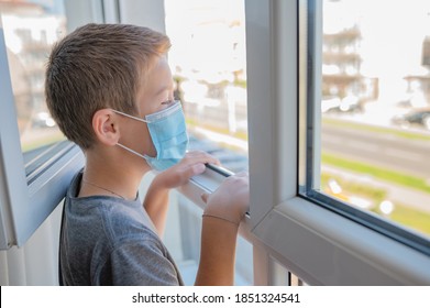 jongen 11 jaar oude schooljongen die thuis een medisch masker draagt, kijkt door het quarantainethema van het raam