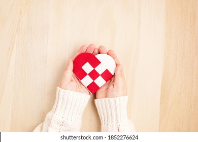 Dando el concepto de martes con manos de mujer sosteniendo corazón rojo y blanco, concepto de día de caridad. Idea de donación, filantropía, ayuda y apoyo. Vista superior, endecha plana