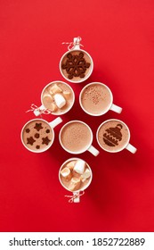 Tassen mit heißer Schokolade mit Marshmallows und Kakaopulverdekor in weißen Tassen auf rotem Hintergrund bleiben Weihnachtsbaumform, Draufsicht