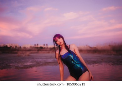 バック グラウンドで青い水着ピンクの空を持つ若い女性