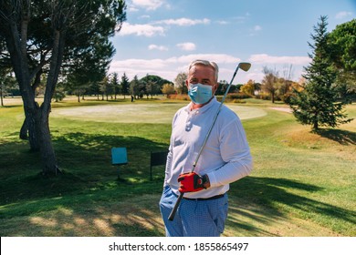 Senior golfer with disposable face mask holding golf club on golf course