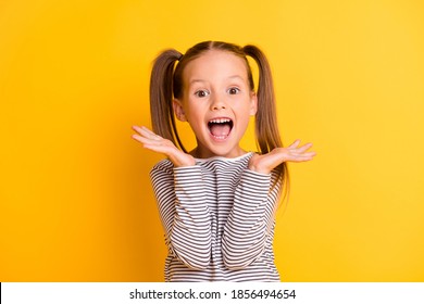 若い興奮してショックを受けた狂気の笑みを浮かべて少女子供子供の肖像画は、黄色の背景に分離された手をつないでいます