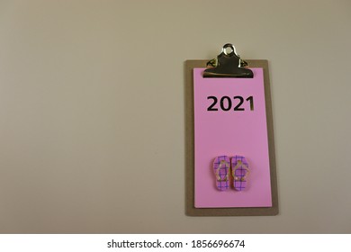 Pink Planner for 2021 year with summer beach slippers on it, on a beige background.  Contemporary positive, enthusiastic plans for sea holidays in 2021.