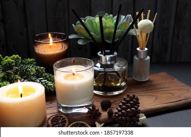 kaca lilin beraroma aromatik yang bagus dan lampu diffusers buluh pada dudukan kayu di atas meja kayu hitam dengan bunga rampai kering, rempah-rempah dan biji pinus di ruang tamu selama pesta tahun baru Natal
