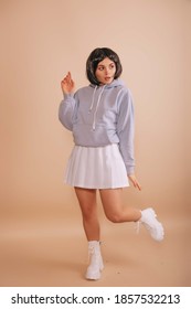 Gadis seksi dengan potongan rambut bob, dengan hoodie dan rok pendek putih berjalan dengan latar belakang krem ​​yang terisolasi. penggemar anime.