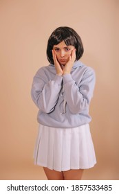 Gadis sedih dengan potongan rambut bob, dengan tudung biru dan rok pendek putih dengan latar belakang krem ​​yang terisolasi. penggemar anime.
