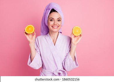 ピンク色の背景に分離されたオレンジ色のスライスを手で保持している髪にタオル ターバンを身に着けている魅力的な健康的な陽気な女の子の肖像画