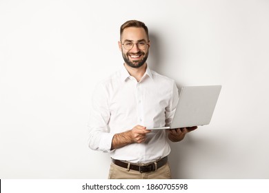 Negocio. Exitoso hombre de negocios que trabaja con una computadora portátil, usa una computadora y sonríe, parado sobre fondo blanco