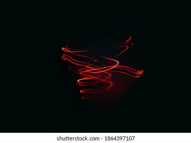黒い背景に赤い色の赤い光る螺旋。創造的なテクスチャー、滑らかな線の渦巻き、暗い背景での動き。長時間露光混合光撮影。創造的な未来的なデスクトップの壁紙。