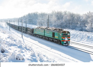 強力な電気機関車 VL8 が、雪に覆われた線路に沿って長い貨物列車を牽引します。晴れた冬の天気。ウクライナの鉄道