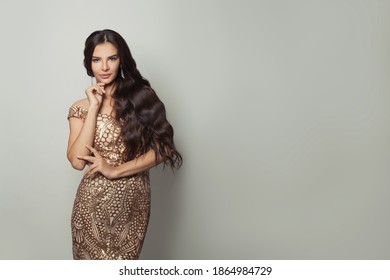 Wanita model fesyen dengan rambut kerinting panjang memakai gaun malam bergaya pada latar belakang putih