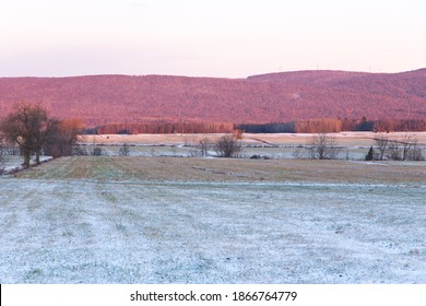 Campos cubiertos de polvo de nieve fresca, con torres de energía en las montañas Laurentian en un fondo de enfoque suave visto durante un amanecer de la hora dorada del invierno, Ciudad de Quebec, Quebec, Canadá